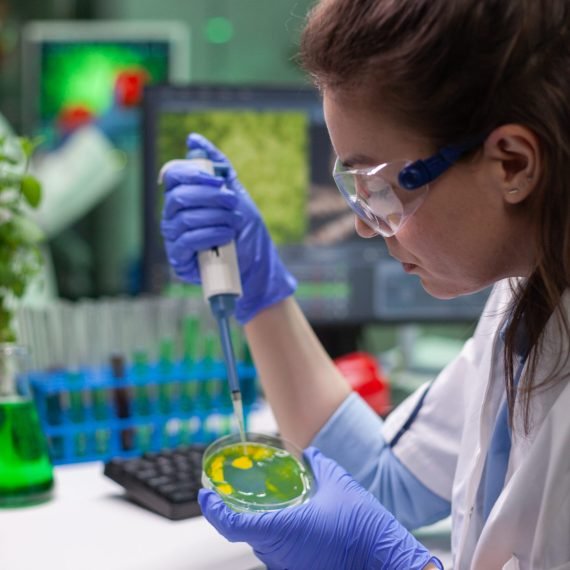 Chemist woman taking dna liquid from test tube with micropipette putting in petri dish analyzing genetic mutation. Biologist researcher working in pharmaceutical laboratory.